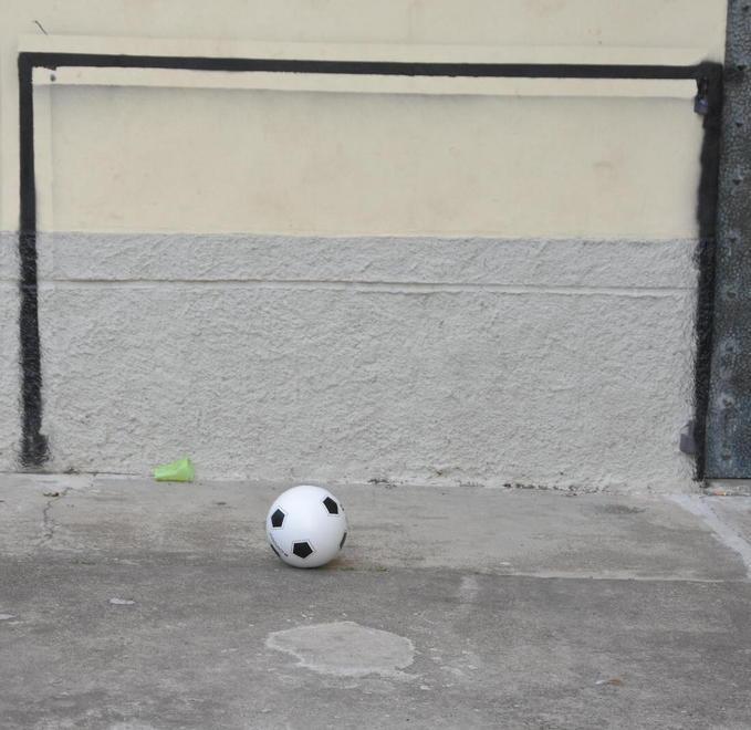 Spara a tre ragazzi che giocano a calcio in piazza 