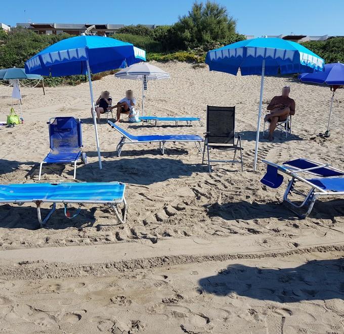 Spiaggia libera occupata con ombrelloni e lettini 