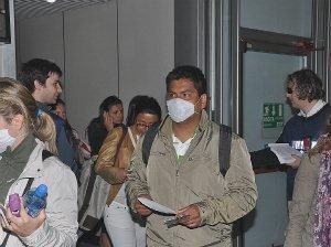 Viaggiatori in transito in un aeroporto si proteggono dal virus con le mascherine