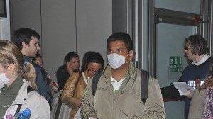 Viaggiatori in transito in un aeroporto si proteggono dal virus con le mascherine