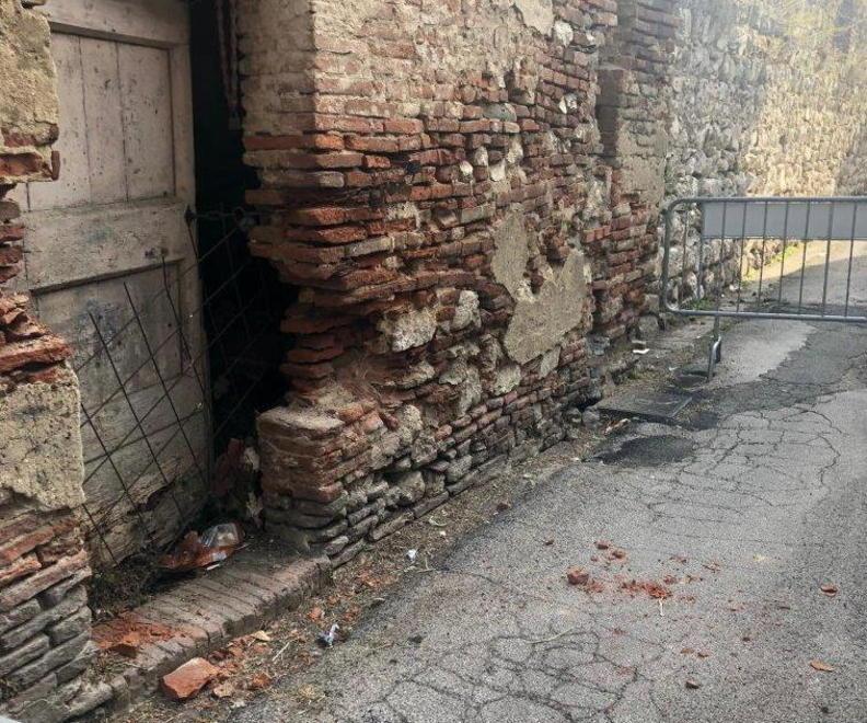 Si staccano mattoni da una casa torre lungo le antiche mura 