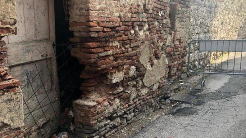 Si staccano mattoni da una casa torre lungo le antiche mura