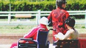 Una badante accompagna un disabile in un parco