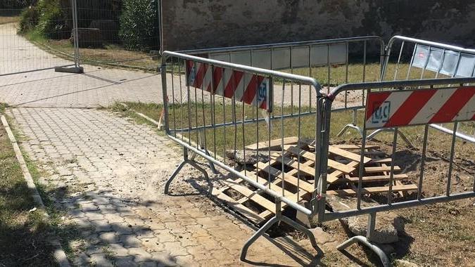 Lavori e buca transennata dove giocano i bambini