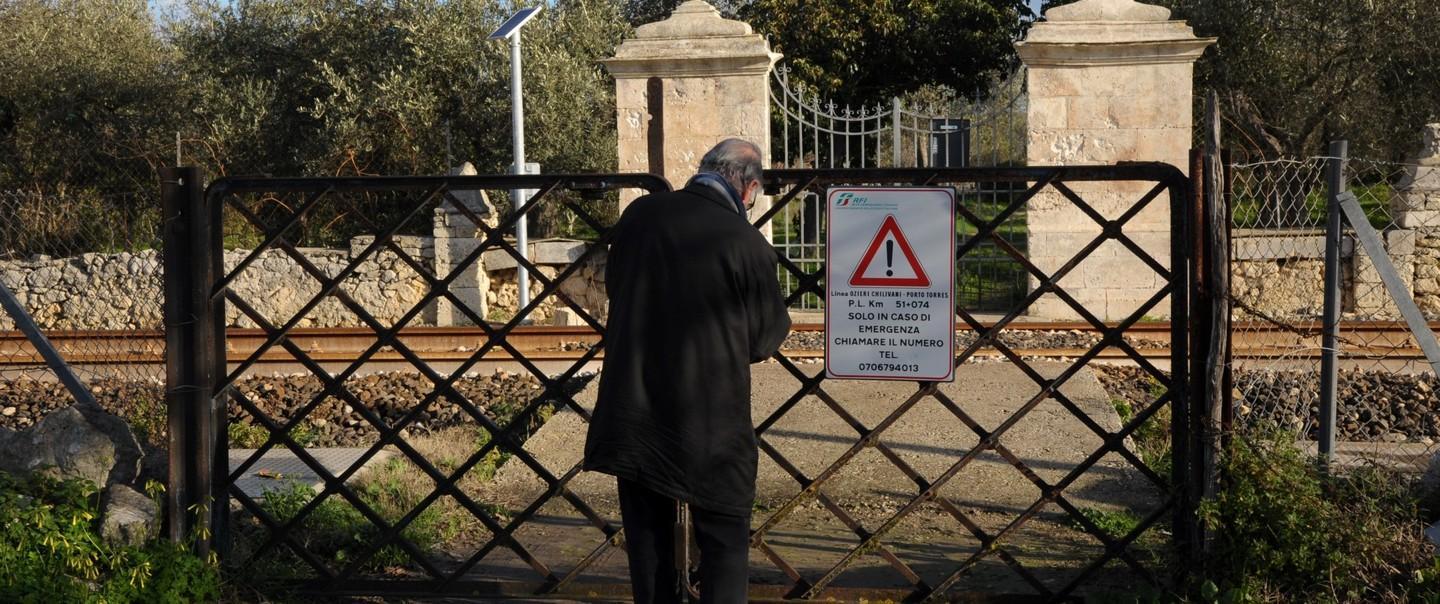 Pietrino Sanna, uno dei proprietari dei terreni a San Giorgio con vista sulle rotaie, apre il cancello per rientrare a casa