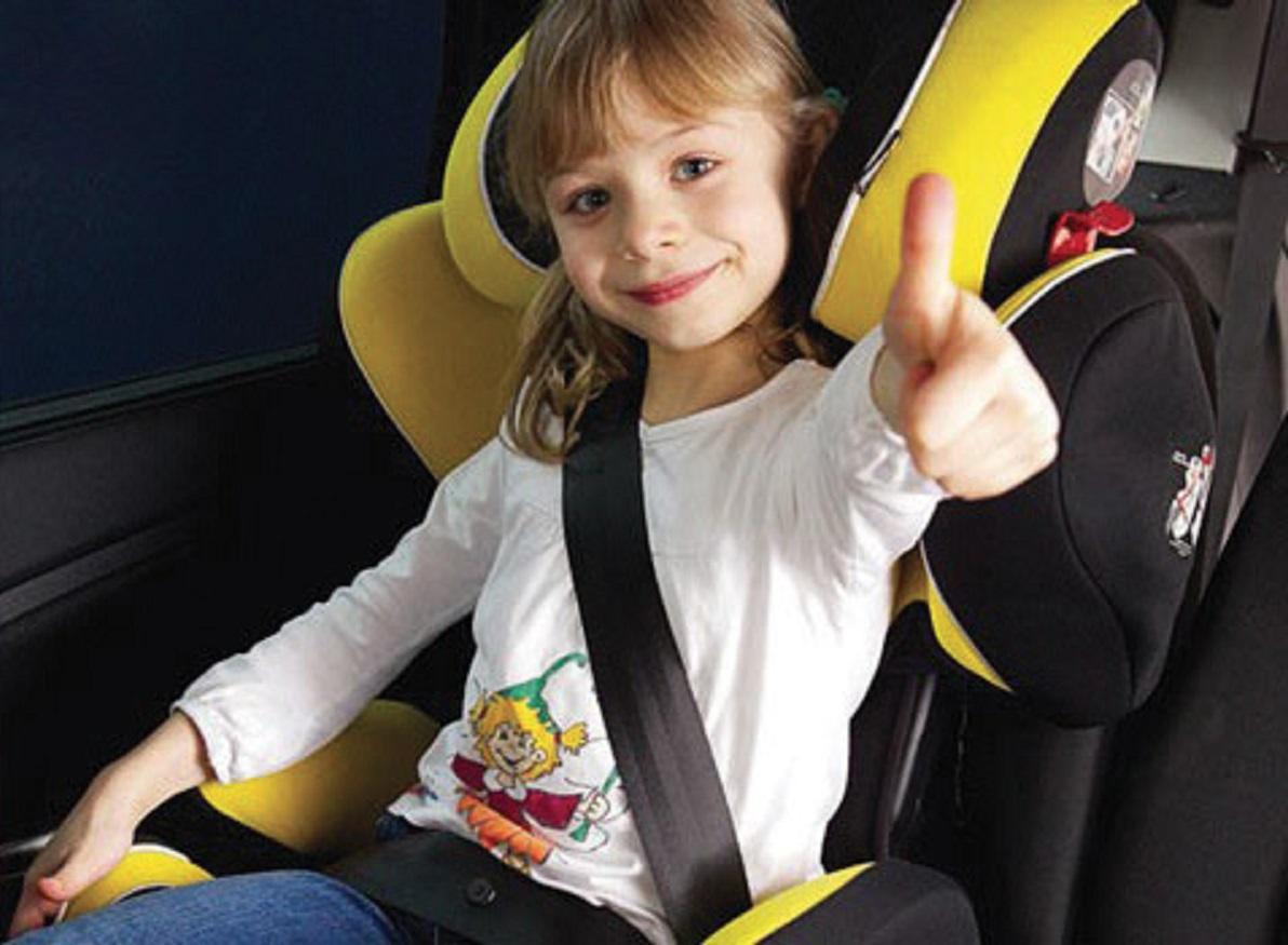 Una bambina correttamente assicurata con seggiolino e cinture di sicurezza