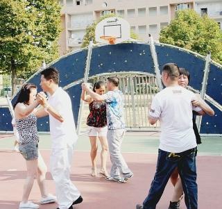 Giovani cinesi ballano ai giardini. In alto, esercizi di tai chi