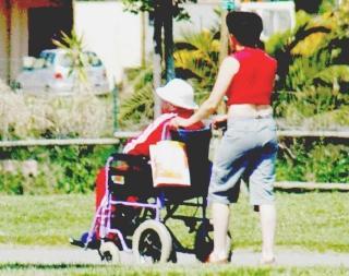 Una badante spinge la carrozzella di una anziana