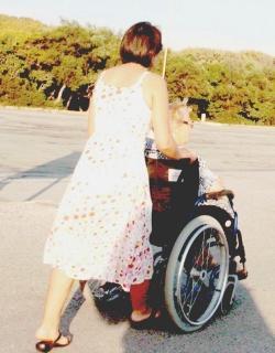 Una badante porta a passeggio un anziano