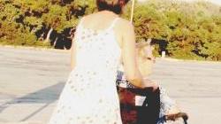 Una badante porta a passeggio un anziano