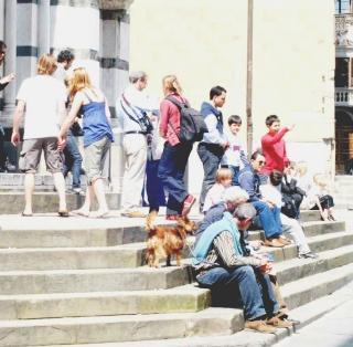 Sopra e in alto turisti in piazza del Duomo e davanti al battistero