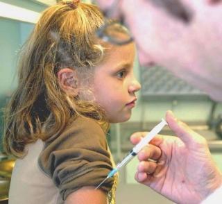 Accanto, la sede dell’Asl Più a sinistra, una bambina attende il vaccino e sotto una dottoressa (Foto d’archivio)