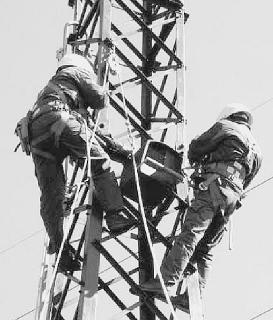 Operai al lavoro su un traliccio della Terna, strutture simili saranno utilizzate per la linea aerea dell’isola d’Elba
