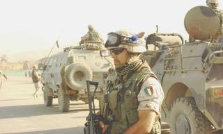 Un militare italiano in missione in Afghanistan davanti a una colonna di mezzi blindati Lince