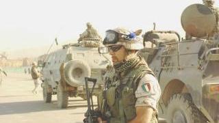 Un militare italiano in missione in Afghanistan davanti a una colonna di mezzi blindati Lince