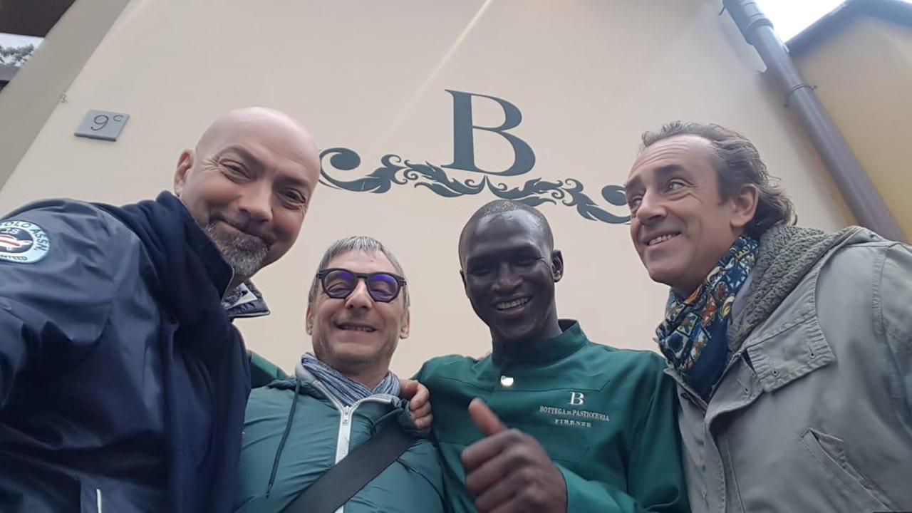 Moussa Ndoye con tre clienti di fronte all’entrata della Bottega di Pasticceria, a Firenze