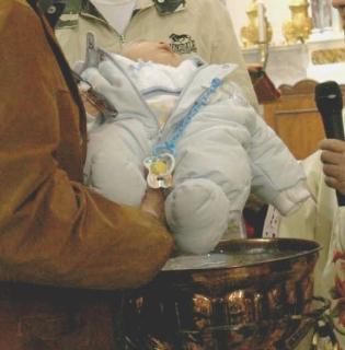 Il battesimo di una bambina con l’aspersione di acqua benedetta