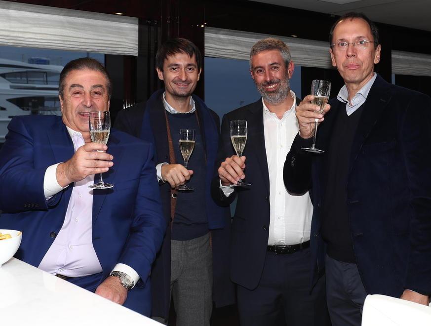 John Staluppi, con la giacca azzurra, a bordo del suo nuovo yacht brinda insieme al designer esterni Giorgio Cassetti, al project manager Nicola Nicolai e al responsabile interior design Domenico Gavagnin