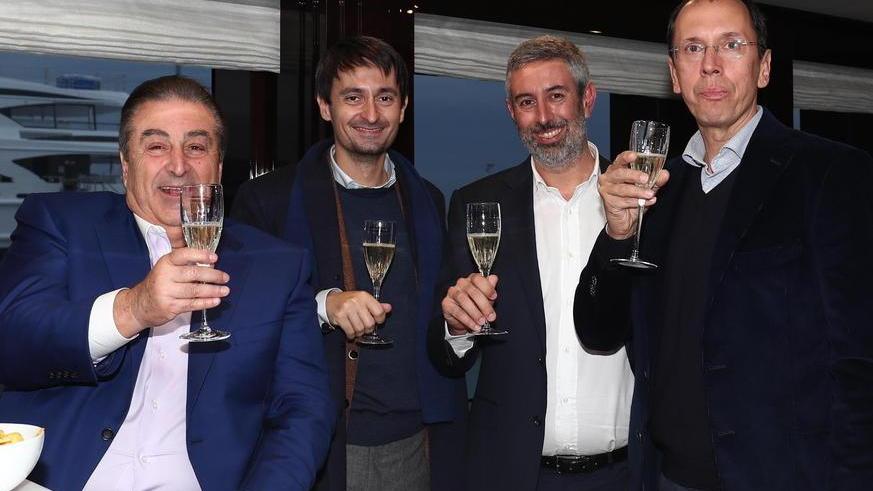 John Staluppi, con la giacca azzurra, a bordo del suo nuovo yacht brinda insieme al designer esterni Giorgio Cassetti, al project manager Nicola Nicolai e al responsabile interior design Domenico Gavagnin