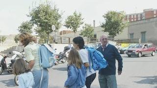Un anziano controlla l’attraversamento dei bambini all’uscita di scuola