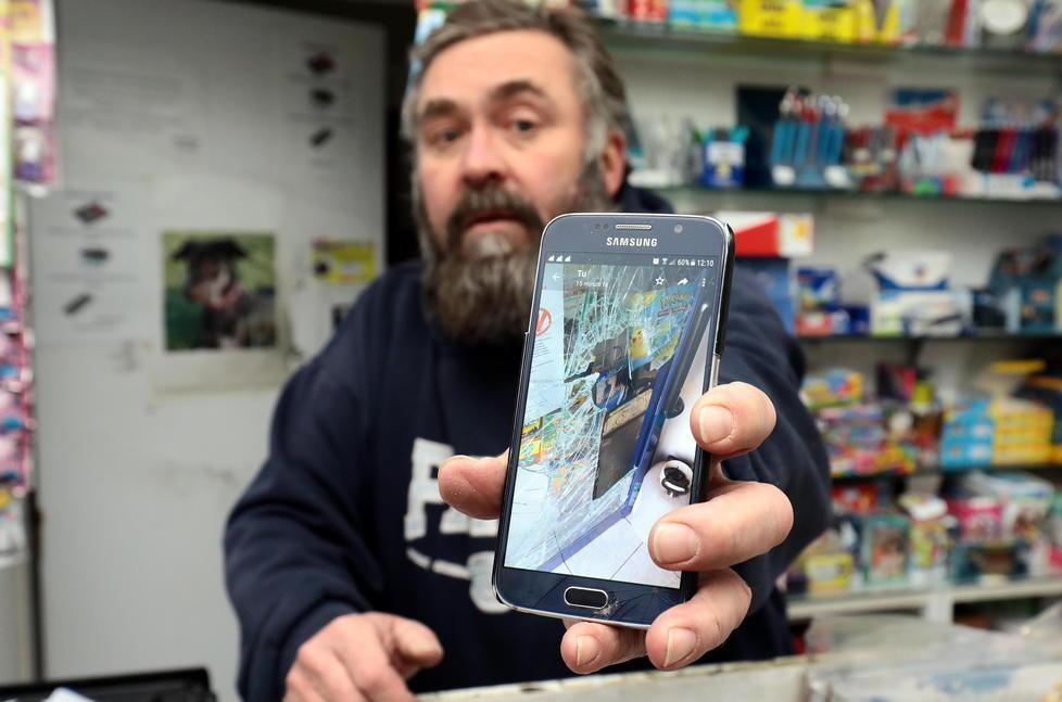 Giorgio Giorgi mostra sullo smartphone la vetrina della sua edicola sfondata dai ladri (Foto Agenzia Carlo Sestini)