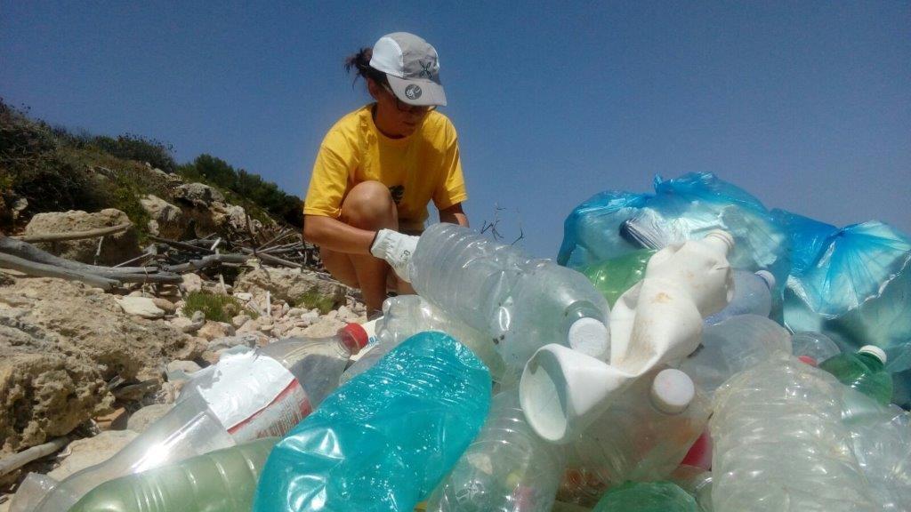 Una volontaria di Legambiente raccoglie rifiuti di plastica sulla spiaggia