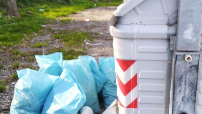Un lavandino e sacchetti di detriti fuori dai cassonetti
