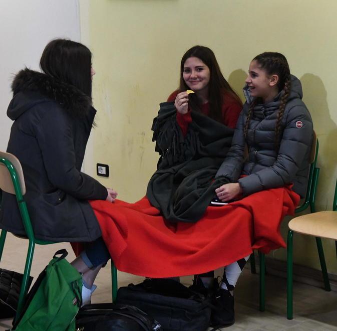 Aule al freddo, gli studenti si scaldano usando coperte nell’atrio della scuola 
