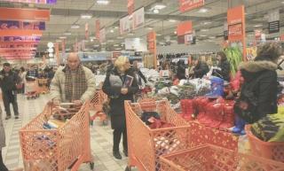 A sinistra, clienti che fanno la spesa all’Ipercoop; a destra, fila alla cassa del discount Eurospin