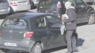 Un immigrato cerca di vendere merce all’auto appena arrivata e a destra l’aiuto a una donna per il passeggino da riporre nell’auto