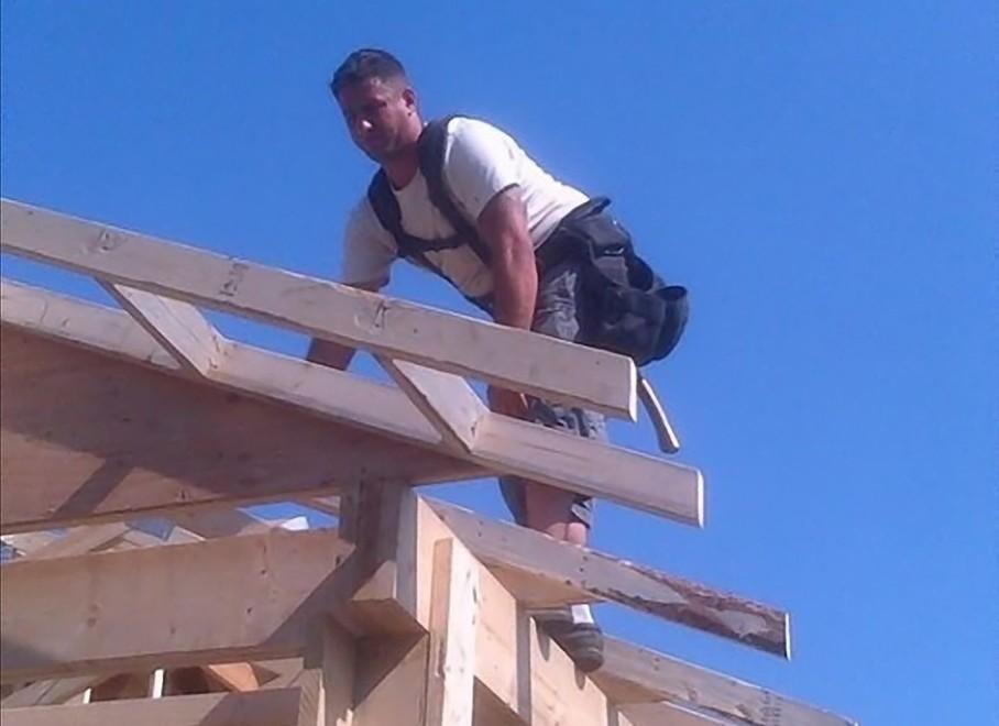Antonio Loreto sopra il tetto di una casa in legno