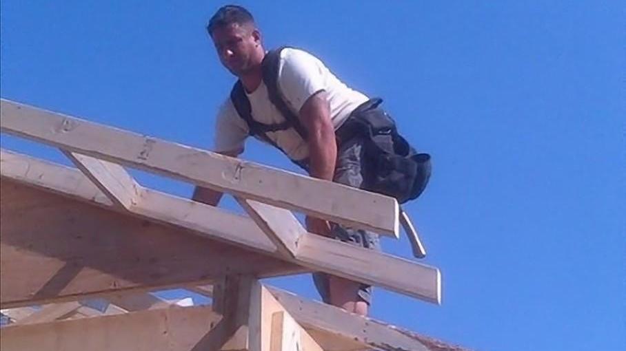 Antonio Loreto sopra il tetto di una casa in legno