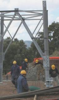 Sopra uno dei tralicci di Terna in costruzione lungo il tracciato aereo della linea, accanto uno striscione contro i tralicci apparso sulla Provinciale a Portoferraio