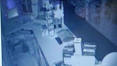 Il ladro ripreso dalle telecamere mentre è all’opera nella tabaccheria; sopra l’inferriata divelta