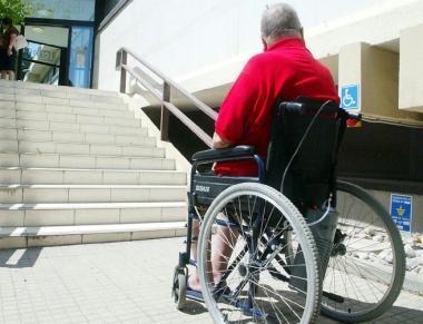 Un disabile in carrozzina davanti a una barriera architettonica    