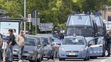 Lo schieramento delle forze dell’ordine e, sopra, uno degli occupanti sul tetto dello stabile