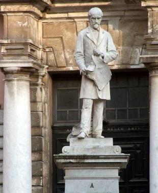 La statua di Mazzini e, sopra Maurizio Cattelan