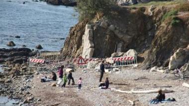 <b>CADUTA DI SASSI. </b>I vigili del fuoco, la polizia municipale e i tecnici della protezione civile effettuano il sopralluogo alla Spiaggia longa mentre i bagnanti prendono il sole Al lato, un esperto dei pompieri sonda la roccia dello scoglio per testarne la stabilità. L’area ieri pomeriggio è stata transennata