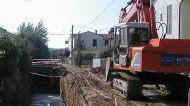 Mezzi al lavoro in un cantiere a ridosso di un corso d’acqua