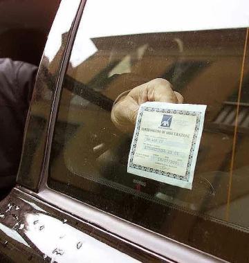Il tagliando dellassicurazione appeso al vetro di unauto 