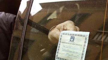 Il tagliando dell’assicurazione appeso al vetro di un’auto