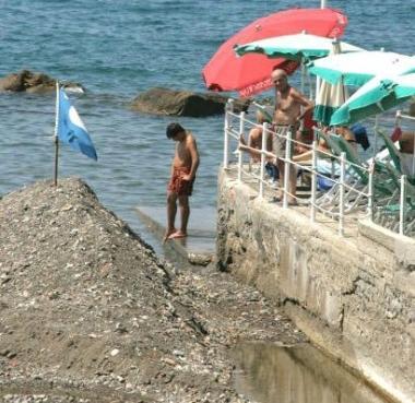 Bandiera blu sul mucchio di rena alla foce del botro 