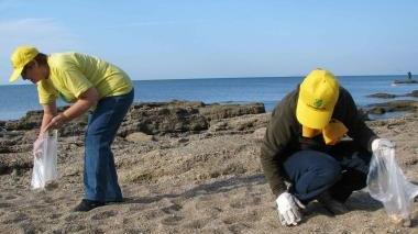 Due volontarie raccolgono cicche su una spiaggia