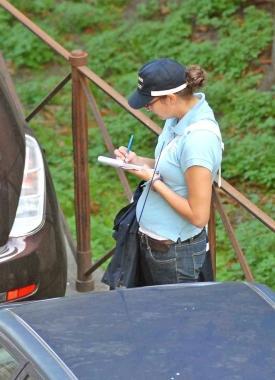 Un vigile ausliario compila un verbale per un divieto di sosta  