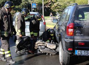 Con la moto sotto un'auto, miracolato
