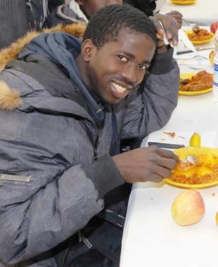 Lamine Coly aveva 20 anni: qui è alla festa della comunità senegalese lo scorso febbraio; a destra i vigili del fuoco lavorano intorno all’auto ribaltata