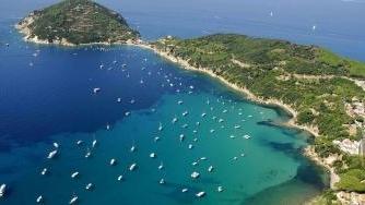 Sopra il sindaco di Portoferraio, Roberto Peria, accanto una panoramica del golfo di Viticcio affollato di imbarcazioni da diporto. Il Comune propone la realizzazione di un campo boe con il Parco