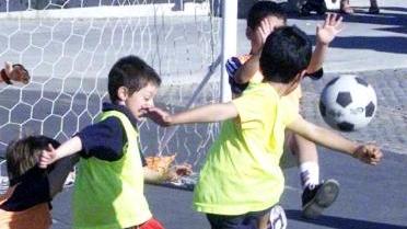 Bimbi che giocano a calcio e sopra un’esibizione di hockey