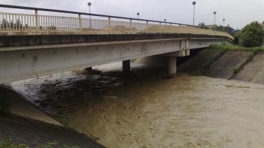 Un vigile del fuoco con la pompa idrovora in uno scantinato allagato e a sinistra il torrente Agliena in piena      