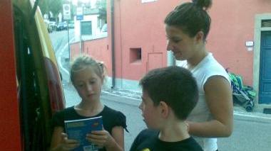 A sinistra Alessia e Alessio insieme a Giulia Rafanelli a destra il bibliobus che durante l’estate gira per le frazioni di Carmignano
